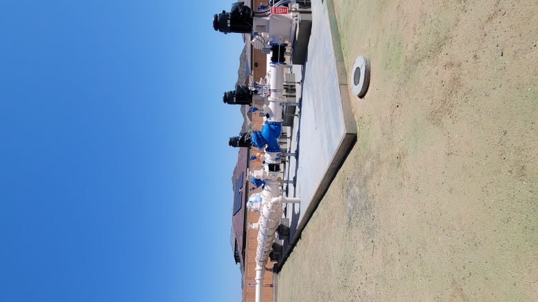 A group of people sitting on a bench in a field.